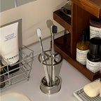 Four-slot stainless steel toothbrush holder standing on a bathroom countertop