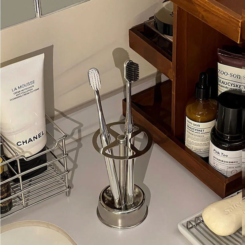 Four-slot stainless steel toothbrush holder standing on a bathroom countertop